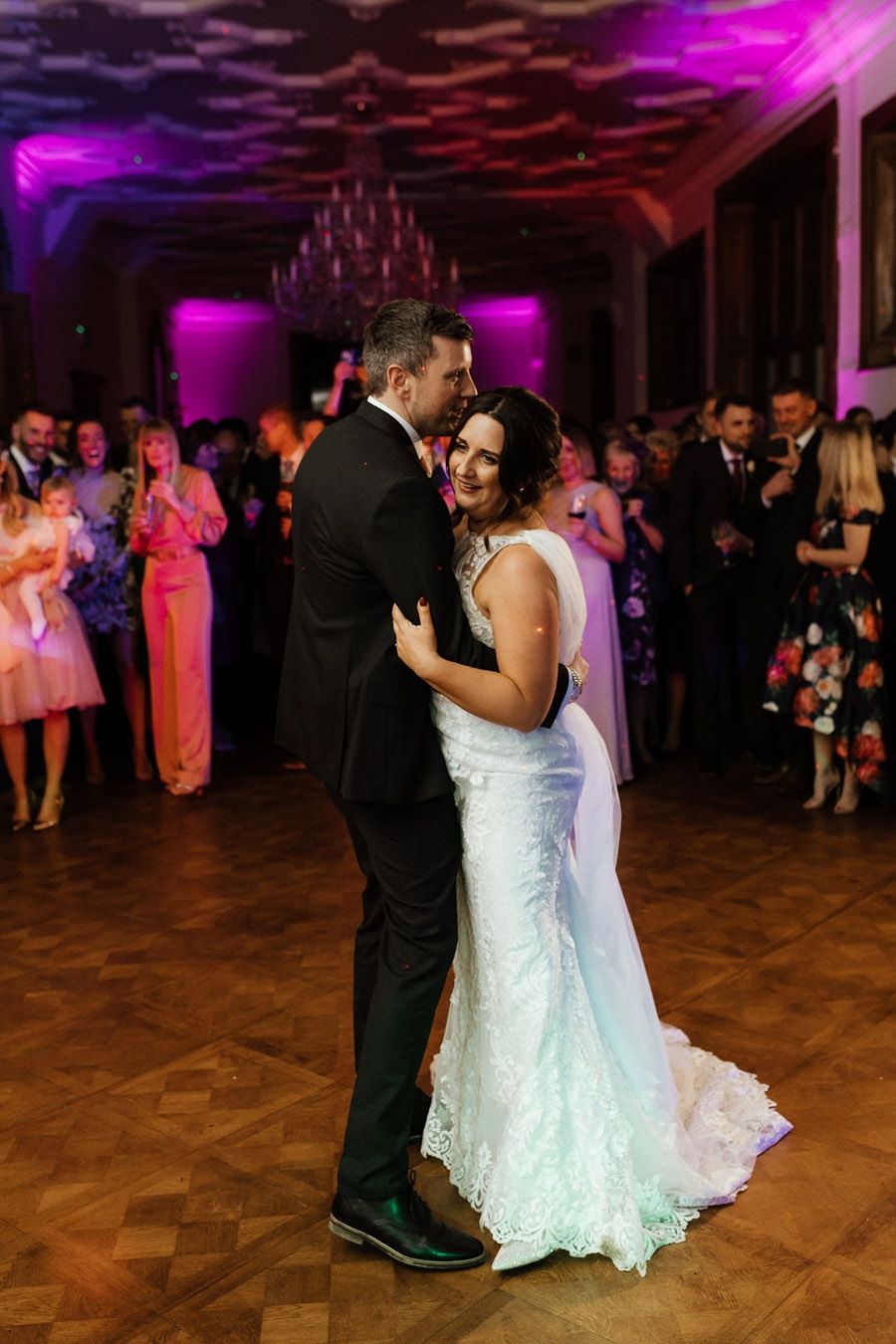 A couple’s first dance in the Ballroom, their guests gathered round beneath the chandelier