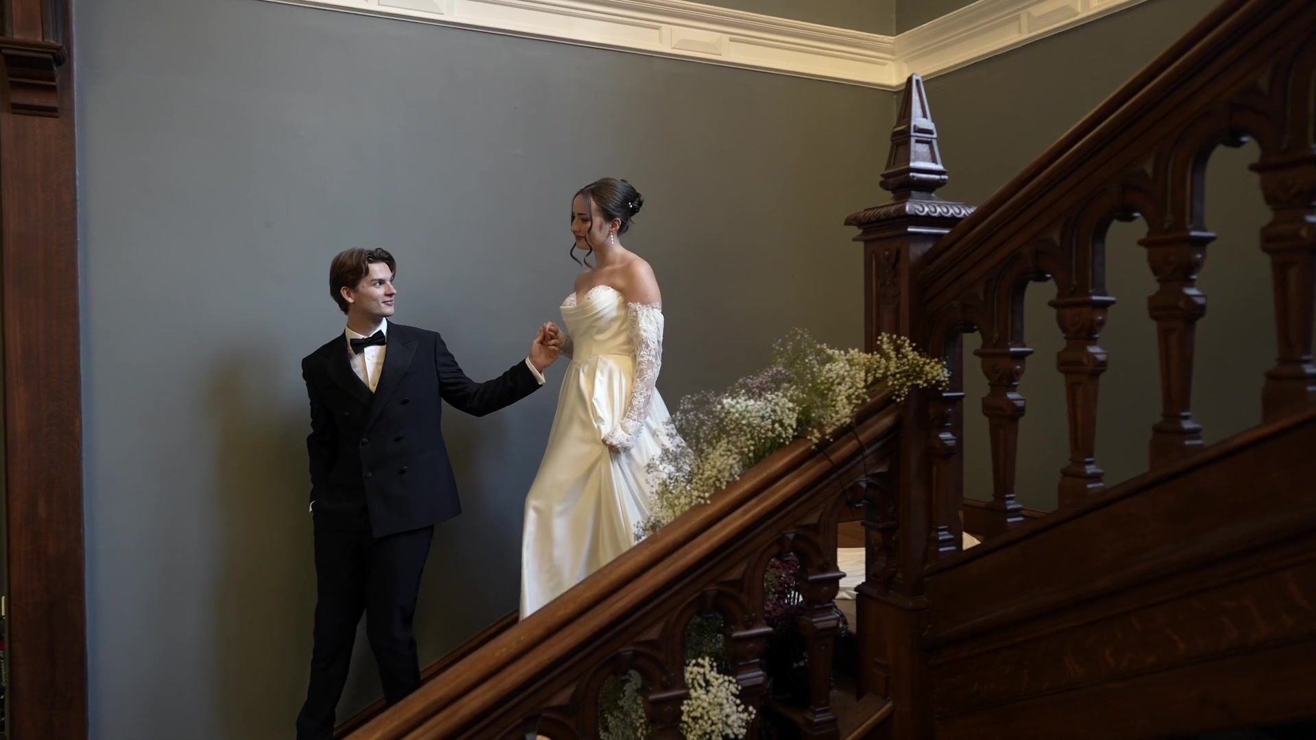 A groom leads his bride down the grand staircase by the hand