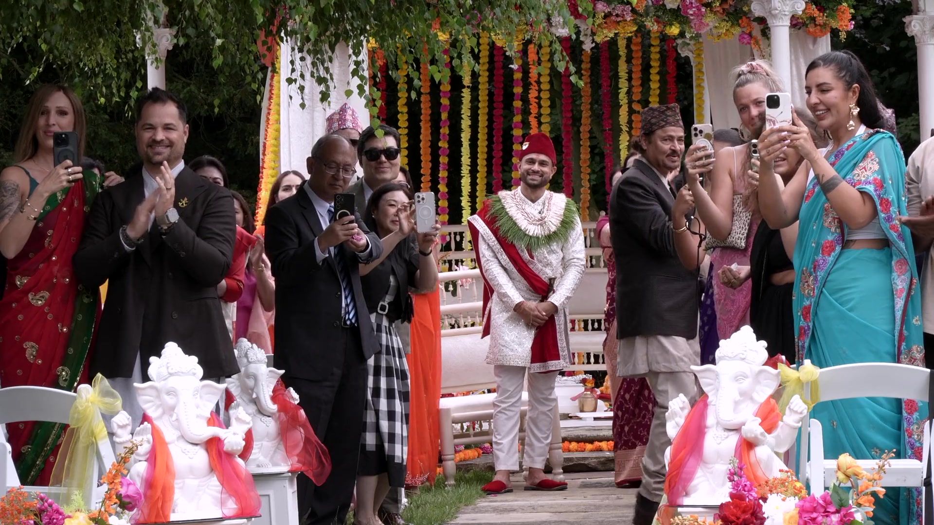 Guests in bright colours celebrate around a Hindu ceremony in the gardens